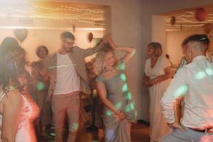 Wedding reception guests dancing and celebrating with colorful lights illuminating the dance floor.