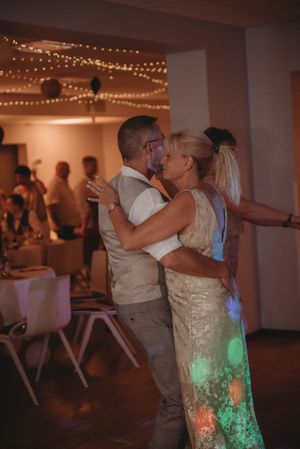 Couple sharing an intimate dance moment under string lights at wedding reception.