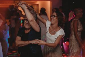 Guests dancing and twirling together at a festive wedding reception with ambient lighting.