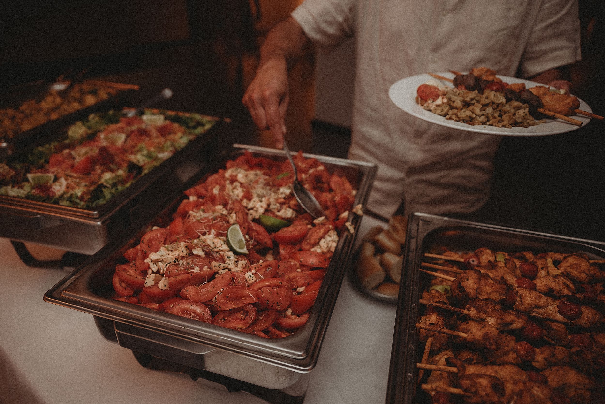 Buffet table displaying various hot dishes in chafing dishes at a catered event.