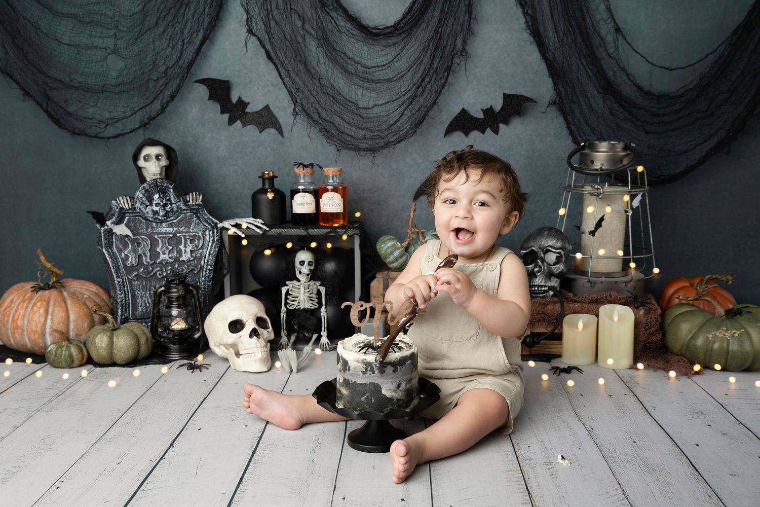 Halloween themed baby photo with spooky decorations, pumpkins, and skeleton props.