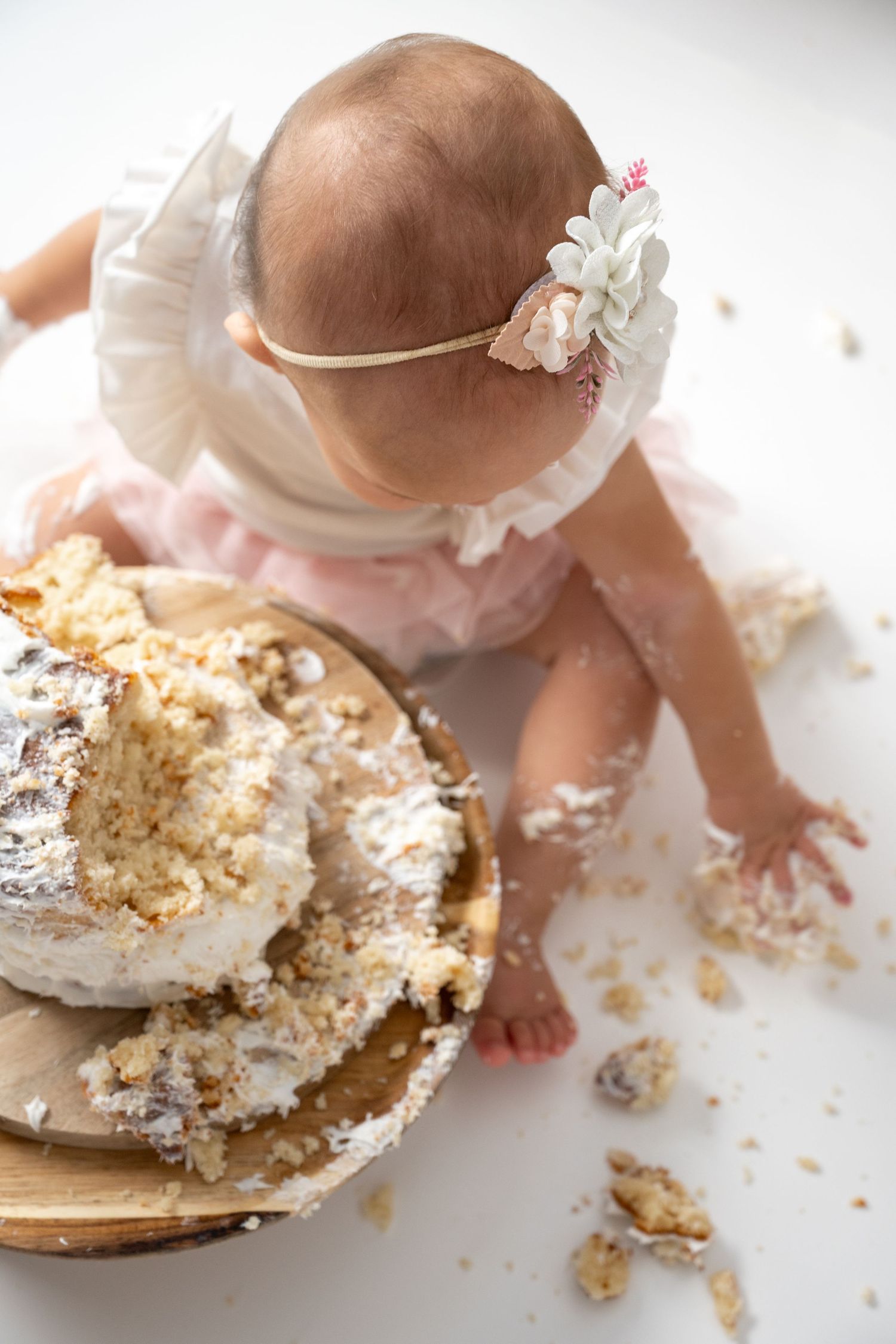 Overhead view of cake smash session with scattered crumbs on wooden platform.