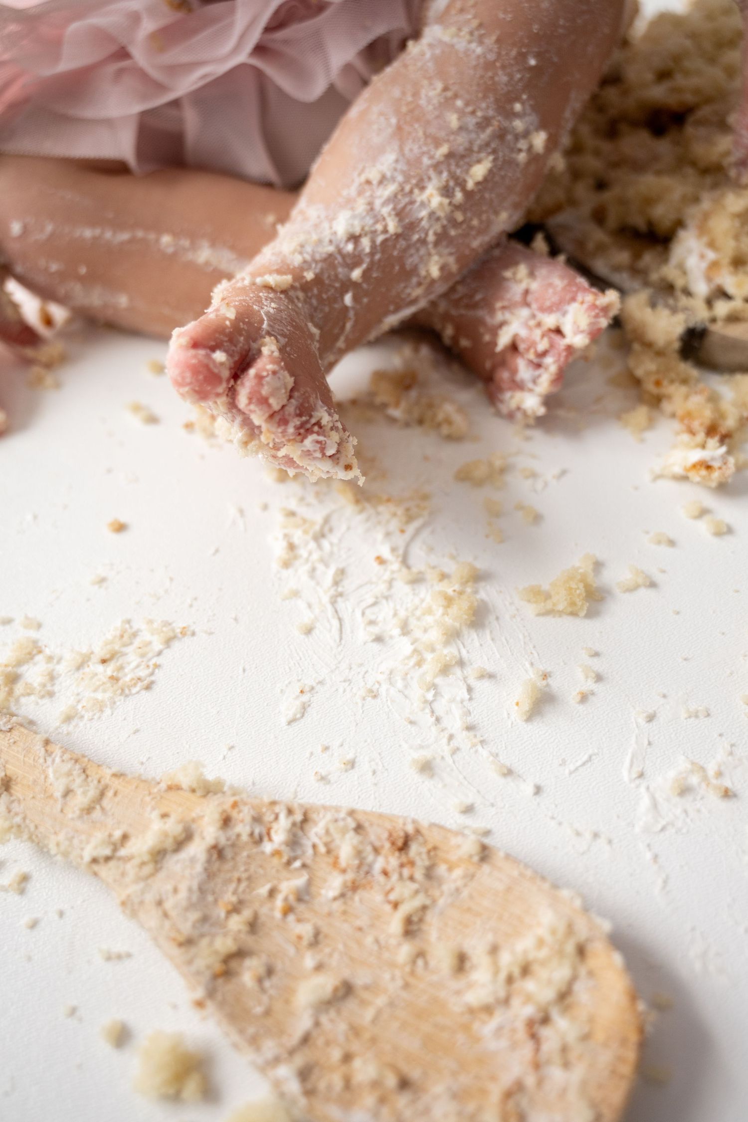 Close-up of messy cake smash aftermath with crumbs scattered on white surface.