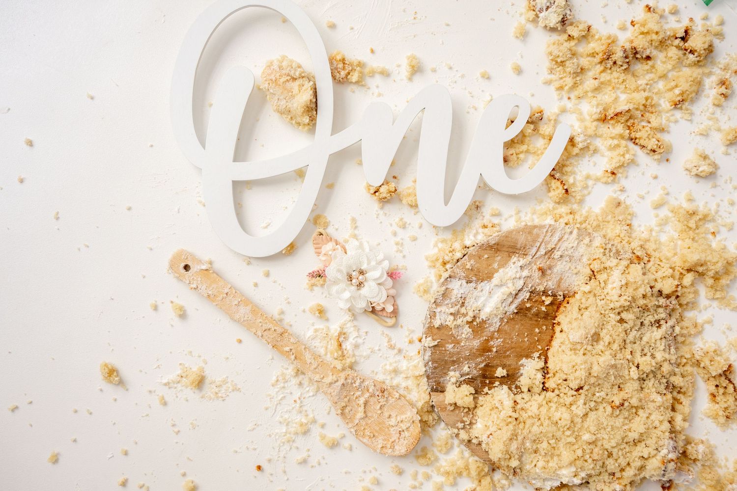 Gold glitter and cake crumbs scattered on white surface during cake smash photoshoot.