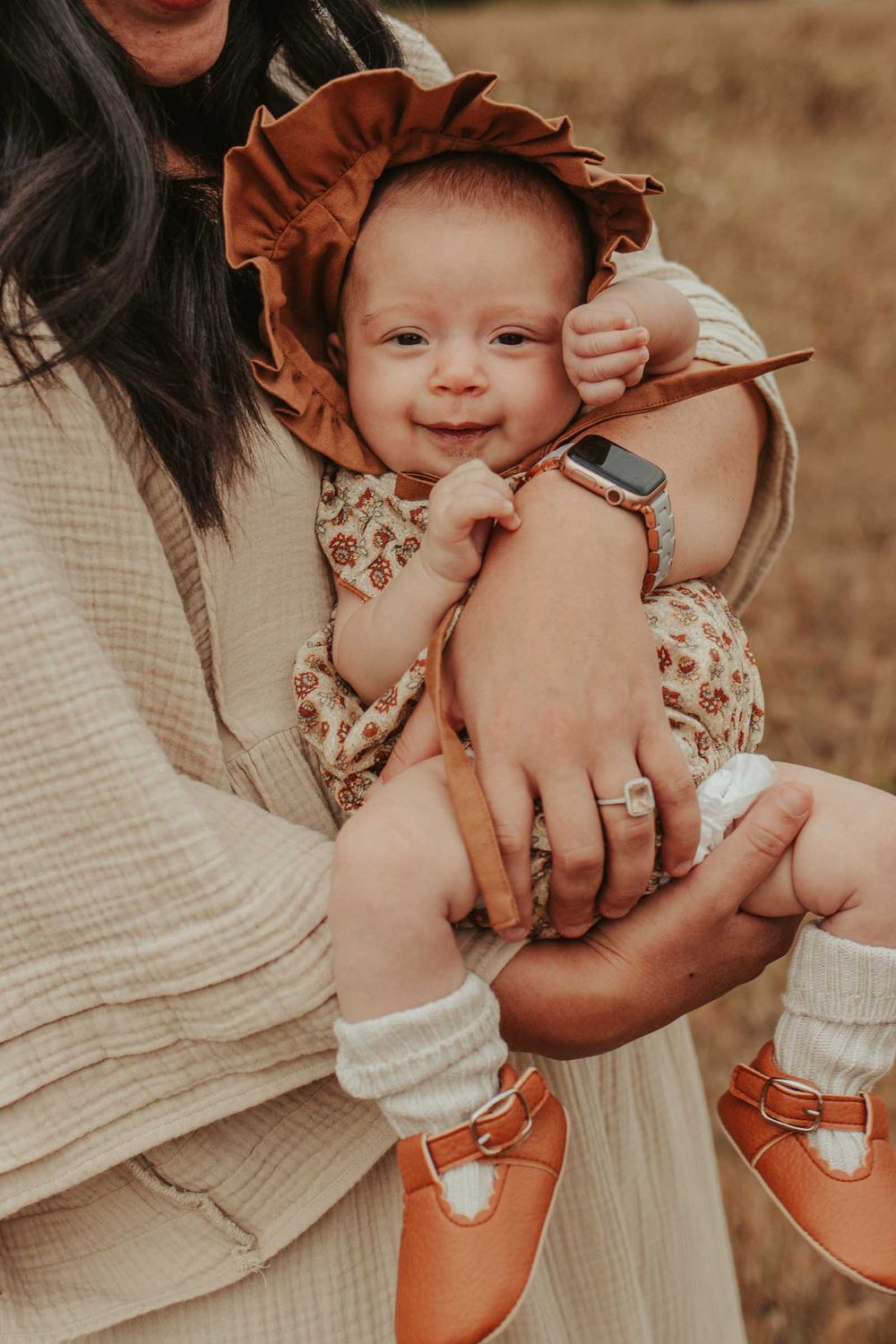mother holding a newborn baby in an open flower field