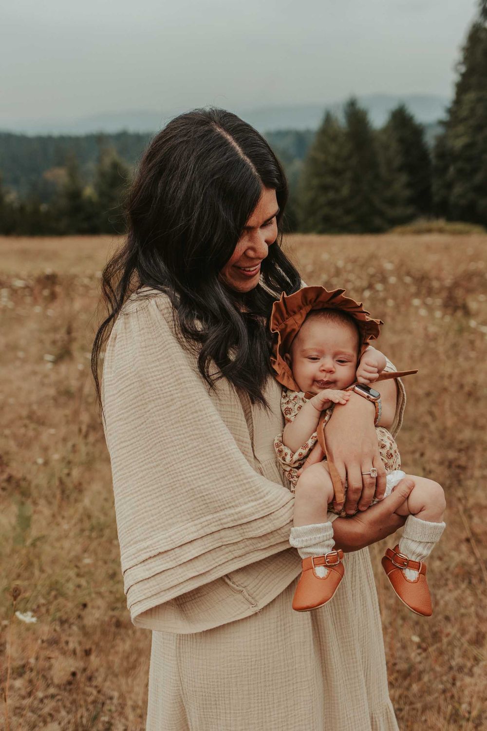 mother holding a newborn baby in an open flower field