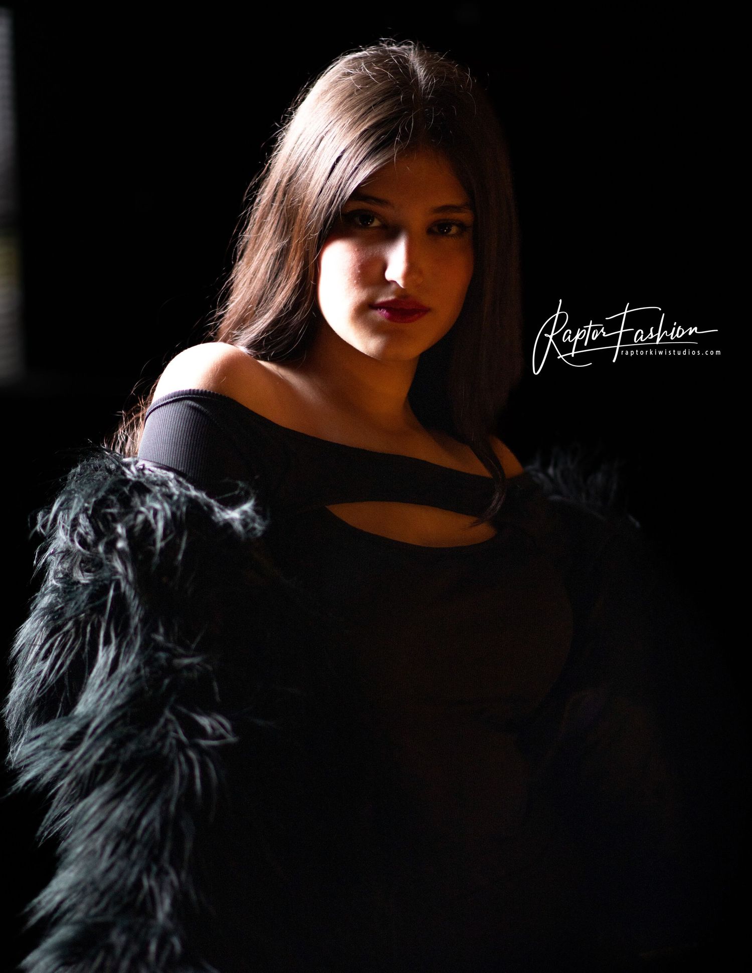 Dramatic portrait featuring black feathered jacket against dark background.