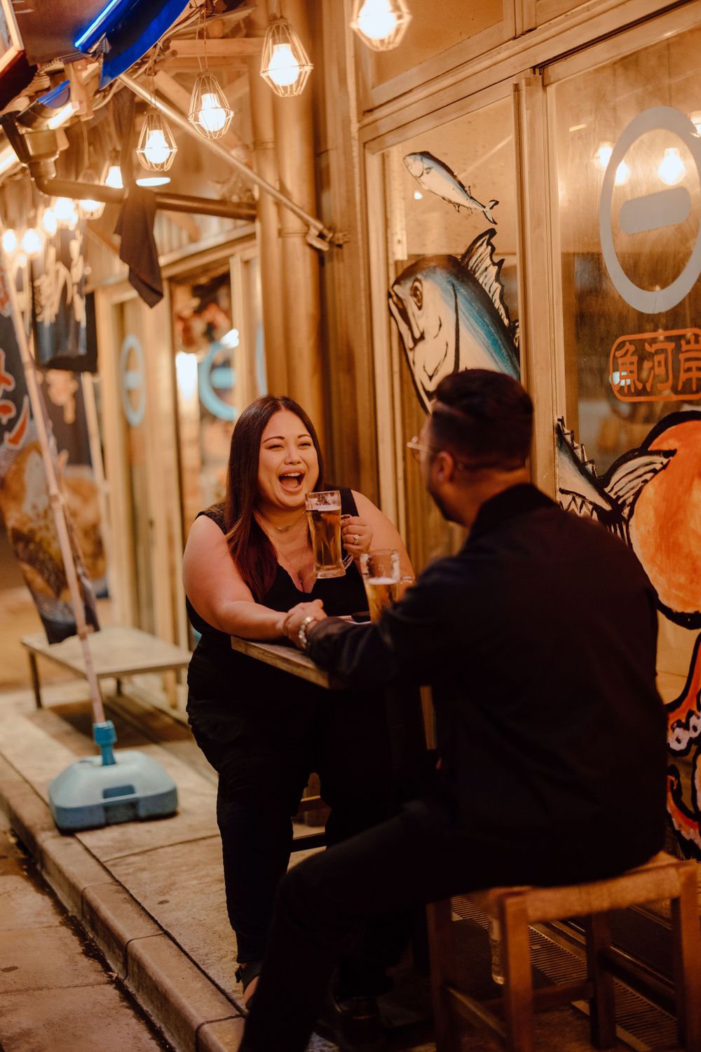 Couple sharing a joyful moment at a cozy restaurant with warm lighting and decorative details in the evening.