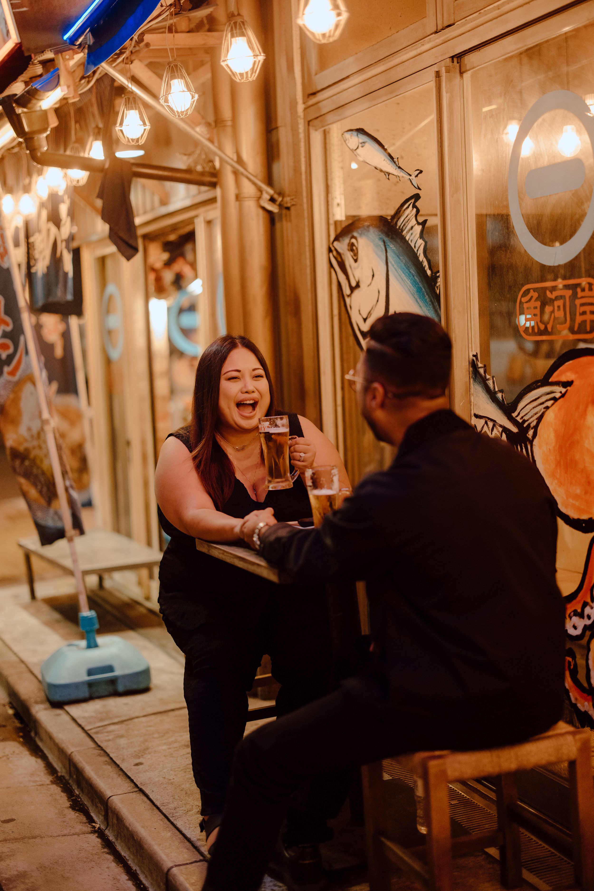 Couple sharing a joyful moment at a cozy restaurant with warm lighting and decorative details in the evening.