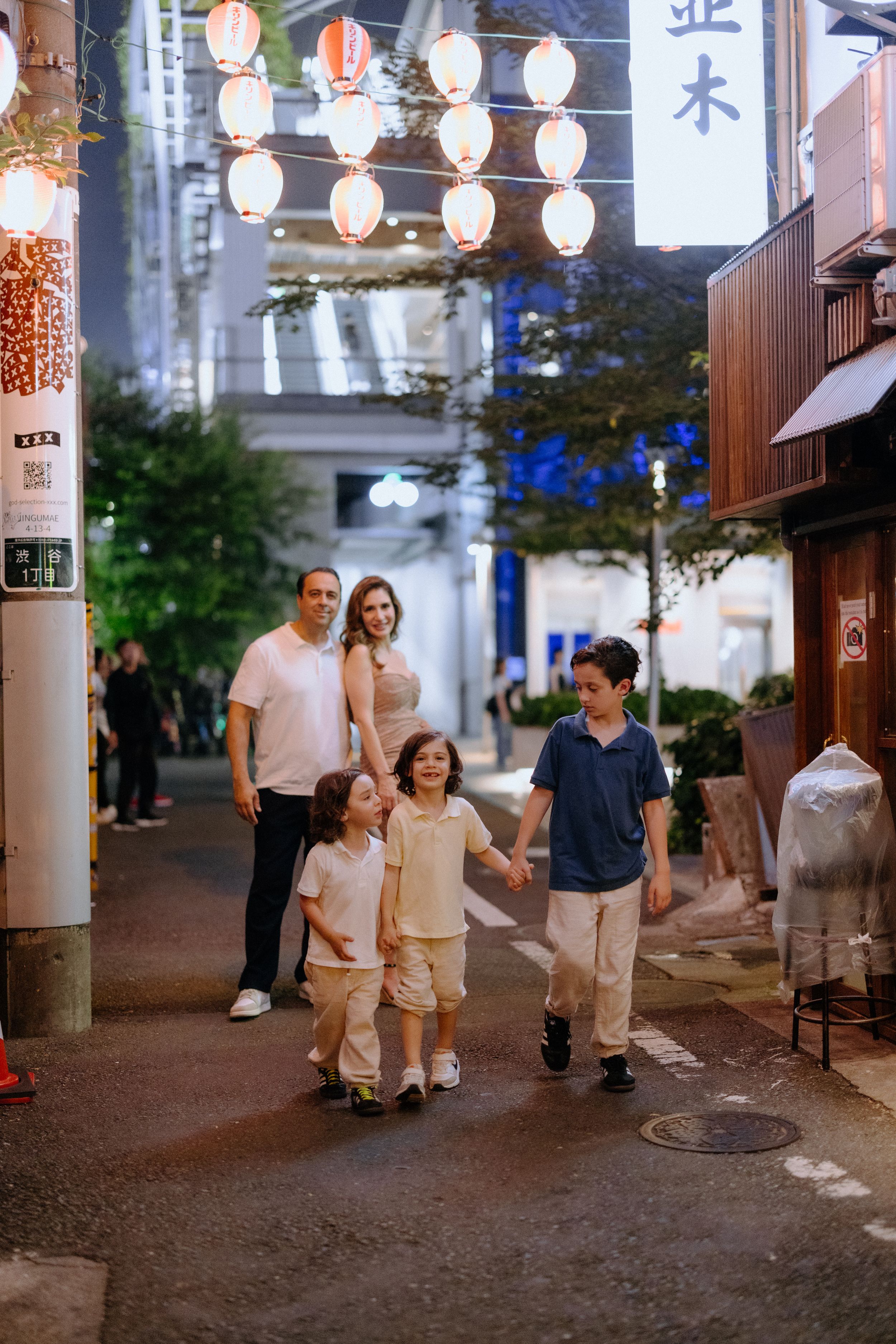 A family walks down a lantern-lit street in Japan's traditional district at dusk.