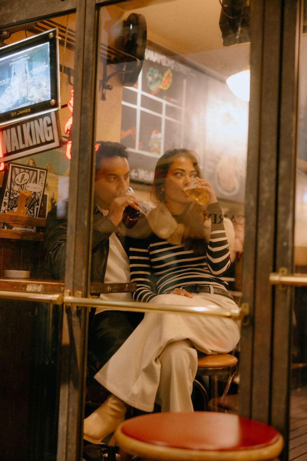 People sitting in a cozy cafe with vintage ambiance captured in warm tones through window glass.