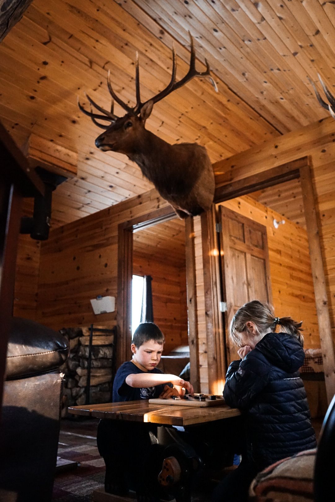 Rustic log cabin interior with mounted deer heads and hunting trophies on wooden walls.