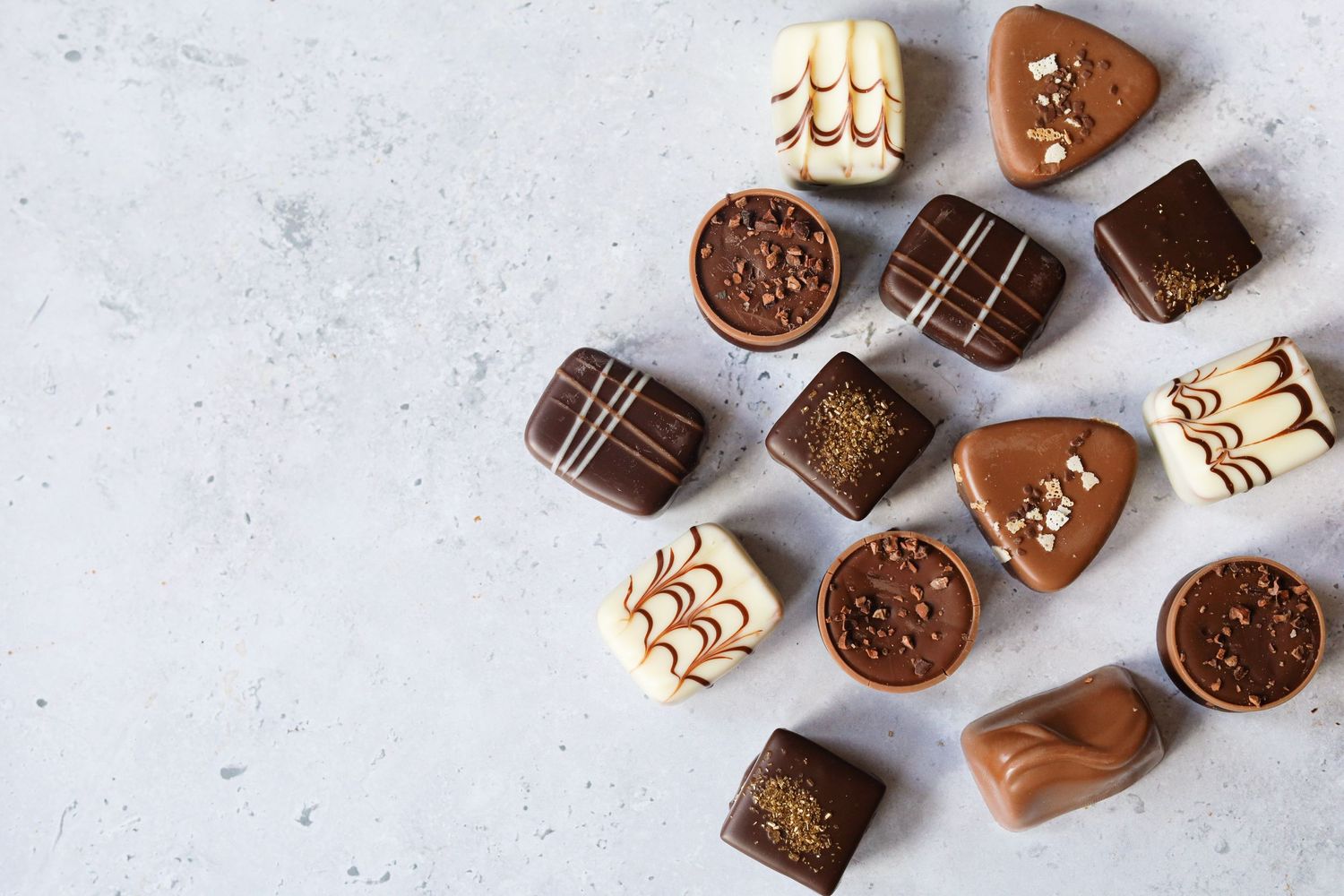 Assorted chocolate candies and cookies displayed on a light surface.