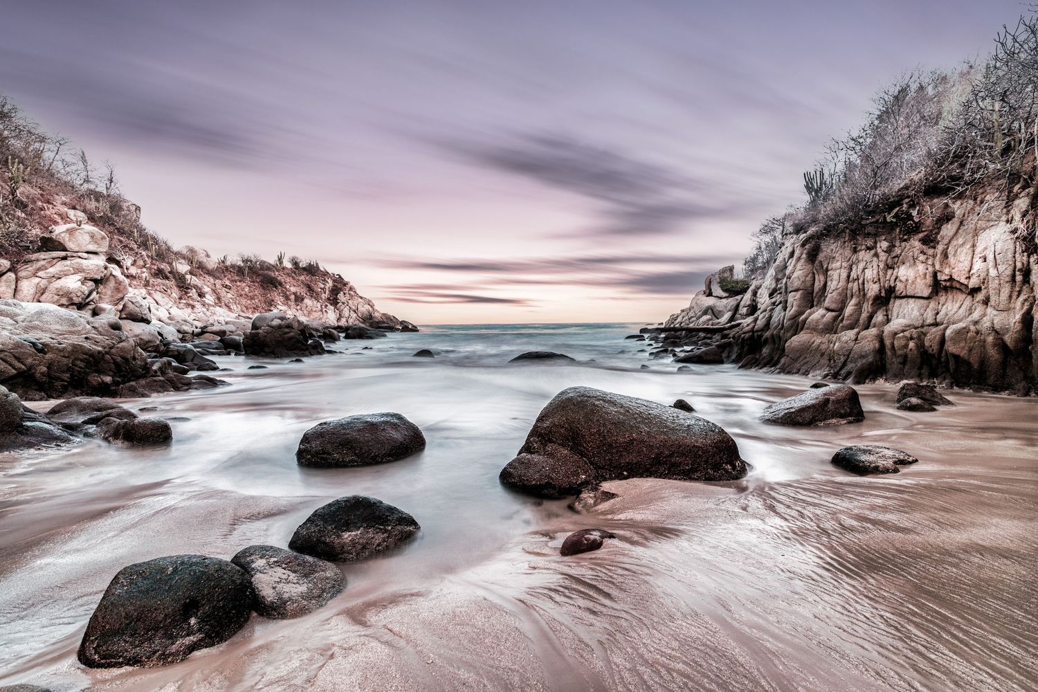 Twilight Tide
The sea gently laps against scattered rocks under a pastel evening sky, where land meets ocean in quiet harmony.