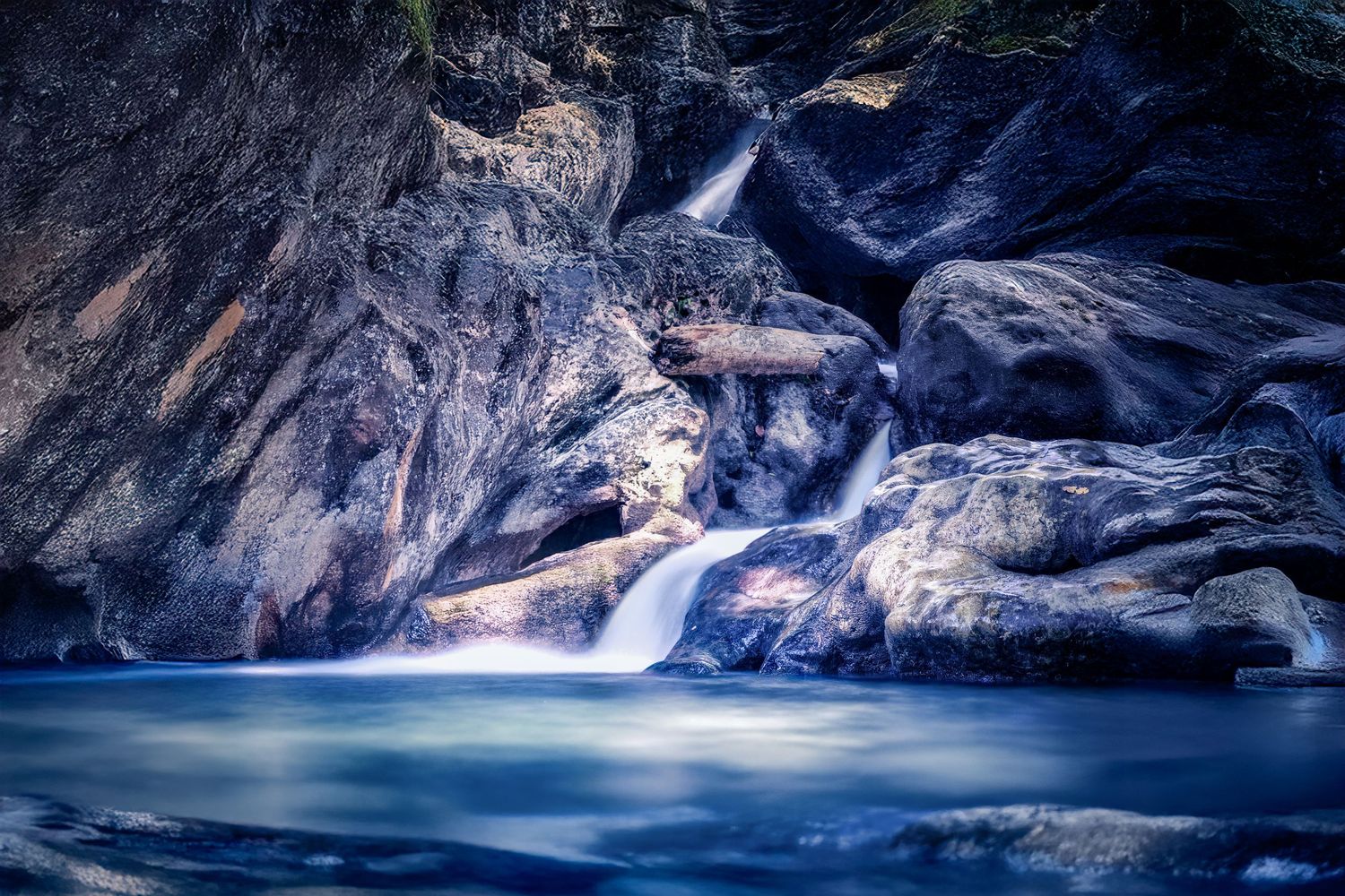 Tranquil Cascade in a Rocky Forest
A gentle stream tumbles over smooth stones in a quiet woodland scene, bathed in soft blue hues.