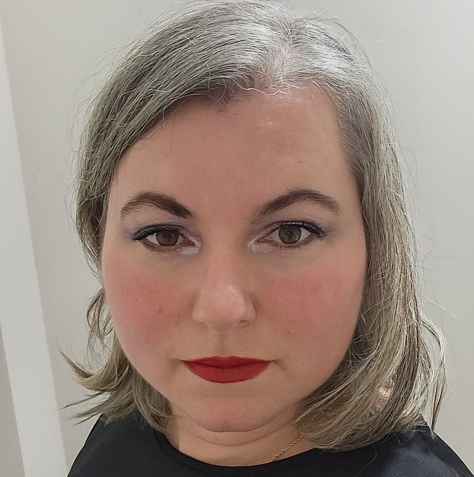Portrait capturing grey hair and red lipstick against a light background.