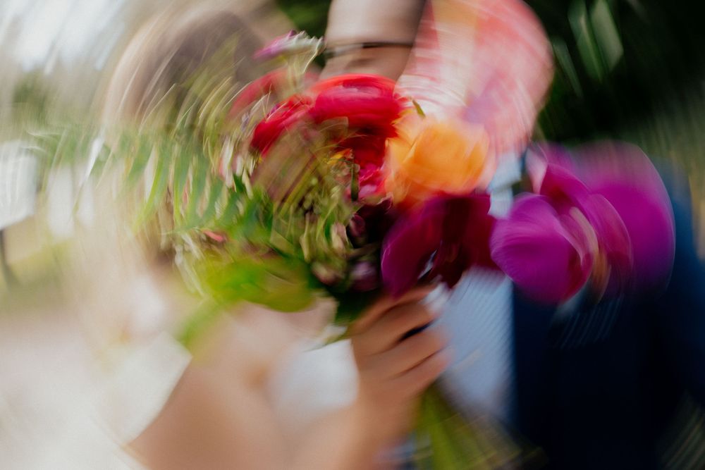 Blurred motion shot of a colorful bouquet of pink, red, and purple flowers being held by a person.