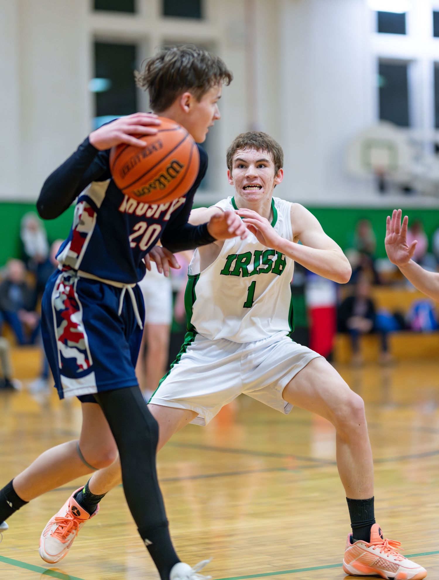 Young basketball players compete for possession of the ball during an intense game on a polished gymnasium floor.