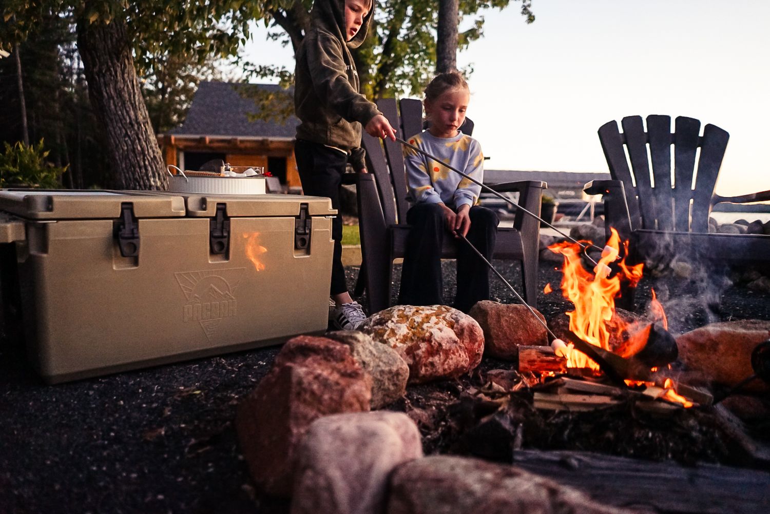 People gathered around a cozy campfire at dusk with chairs and camping equipment.