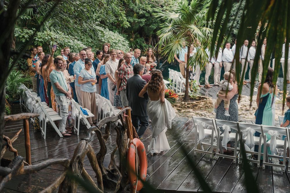 Wedding guests gather on a tropical deck pathway surrounded by palm trees, Sandos Caracol Wedding.
