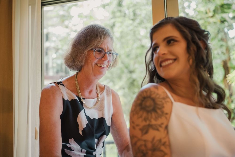 Two women share a joyful moment near a window during wedding preparations, Sandos Caracol Wedding.