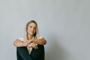 A contemplative portrait showing a person in casual attire against a minimalist background.