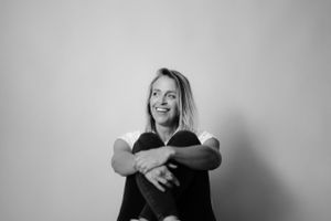 A joyful portrait showing genuine laughter against a simple gray backdrop.