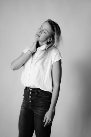Artistic black and white portrait showing person in white button-up shirt with eyes closed.