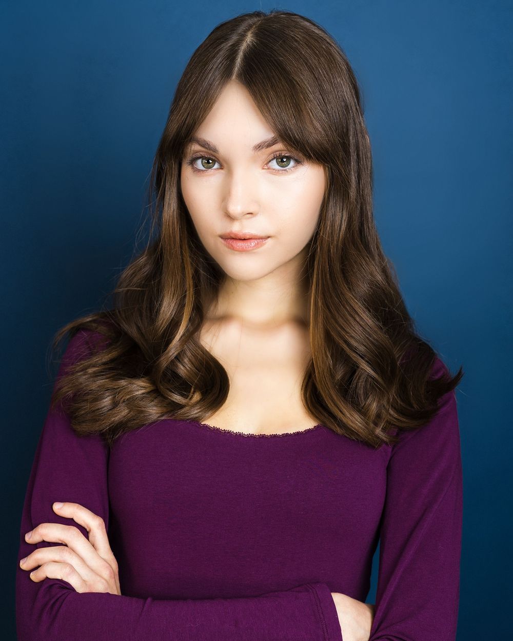 Portrait series against blue background showing person in purple sweater with dark hair in various poses and expressions.