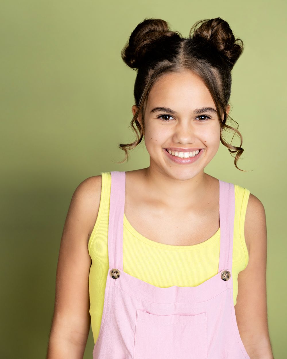 A series of candid portraits showing joyful expressions against a sage green background while wearing pink and yellow.