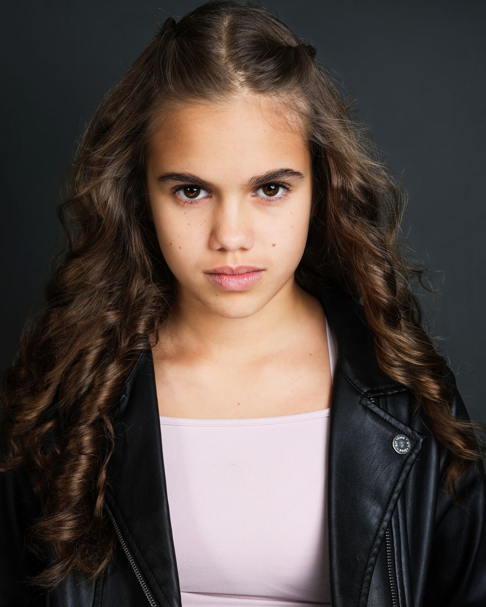 Portrait of someone wearing a black leather jacket against dark background with dramatic side lighting.