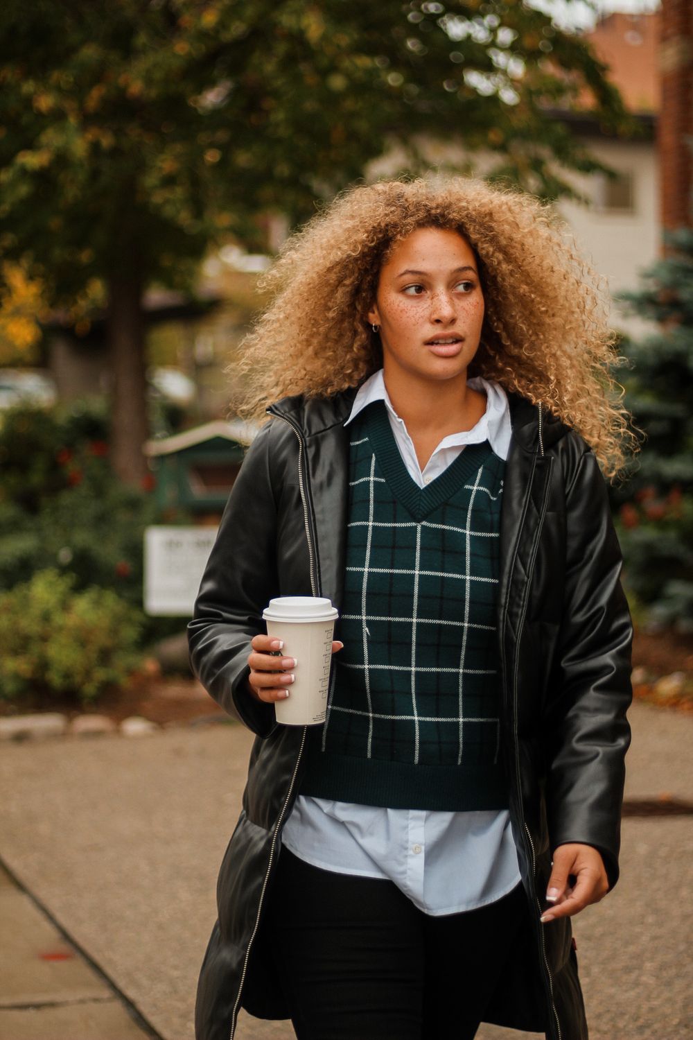 Portrait lifestyle photography of a curly haired model holding a coffee cup walking in the city.