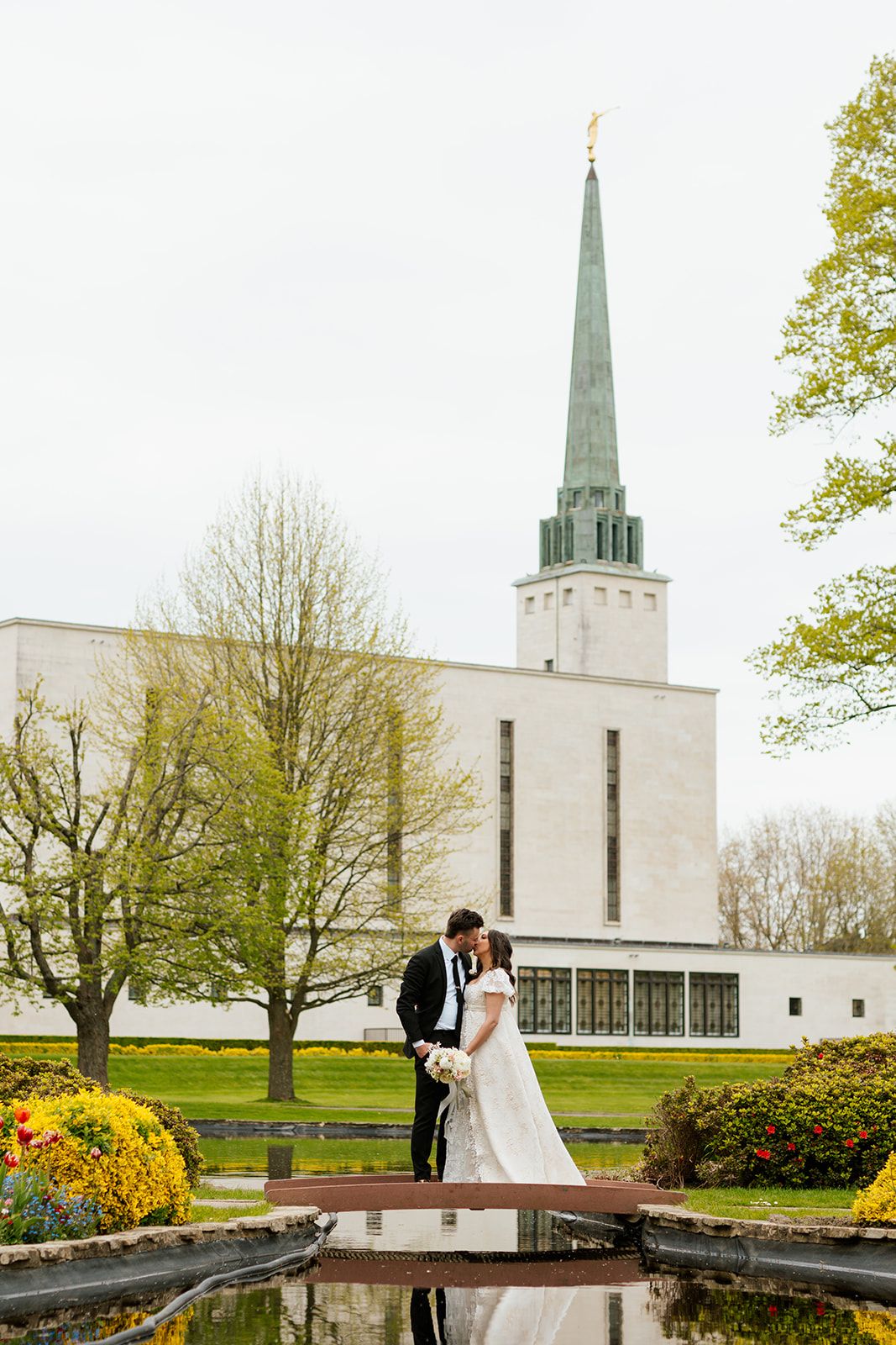 A couple shares romantic moments outside a modern white church with tall spires.