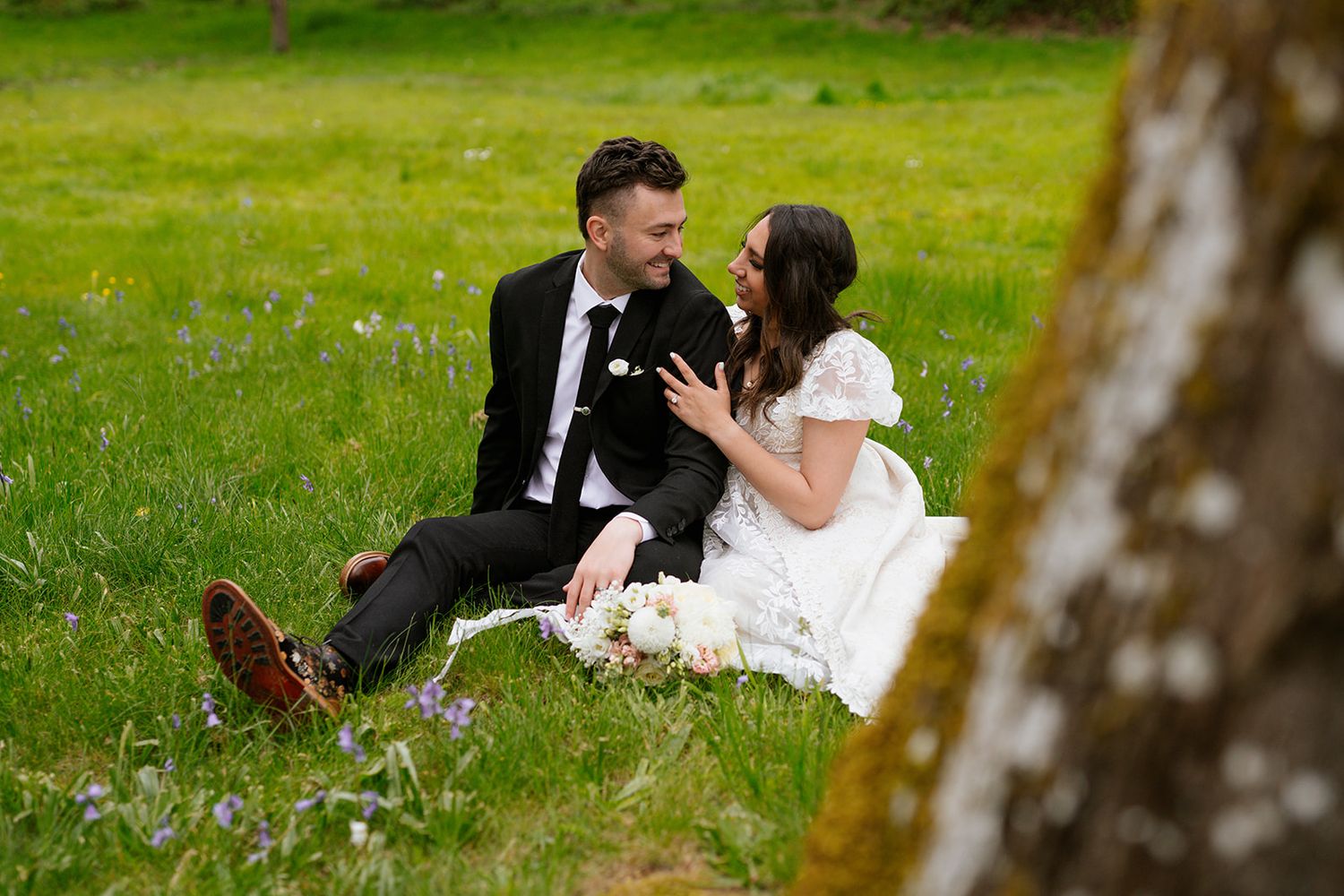 A couple in wedding attire shares intimate moments in a lush green garden setting.