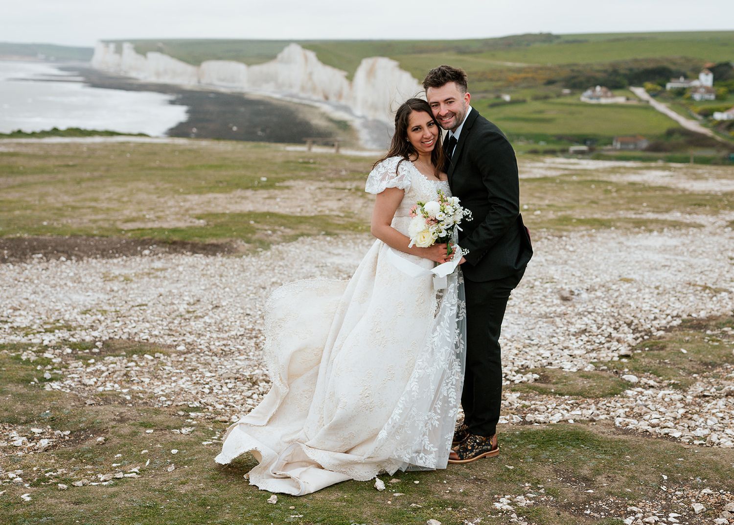 Wedding couple poses on rocky coastal landscape with dramatic ocean views.