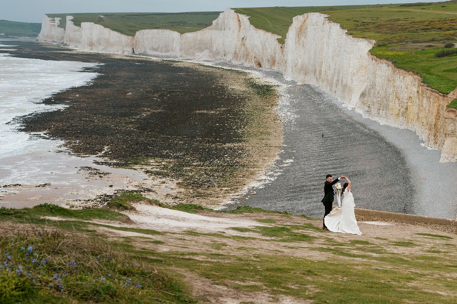 Wedding photos captured along the dramatic white cliffs of Seven Sisters coastline in England.