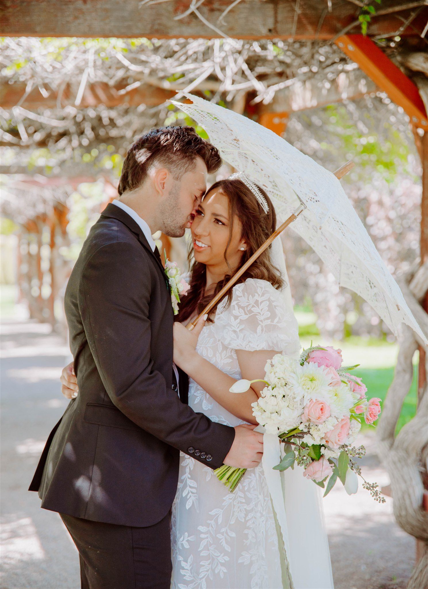 A couple shares tender moments under blooming spring trees with white flowers.
