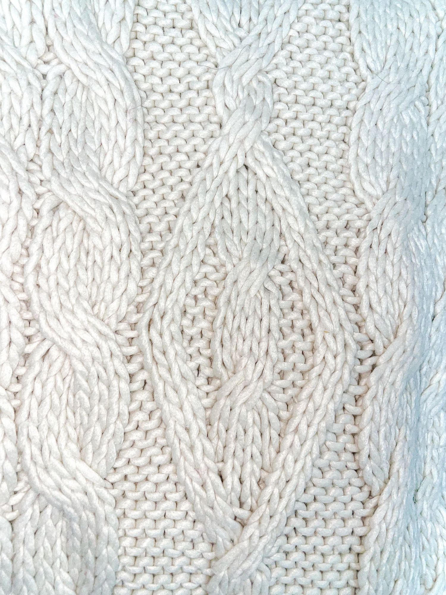 White cable knit fabric pattern showing intricate braided design.