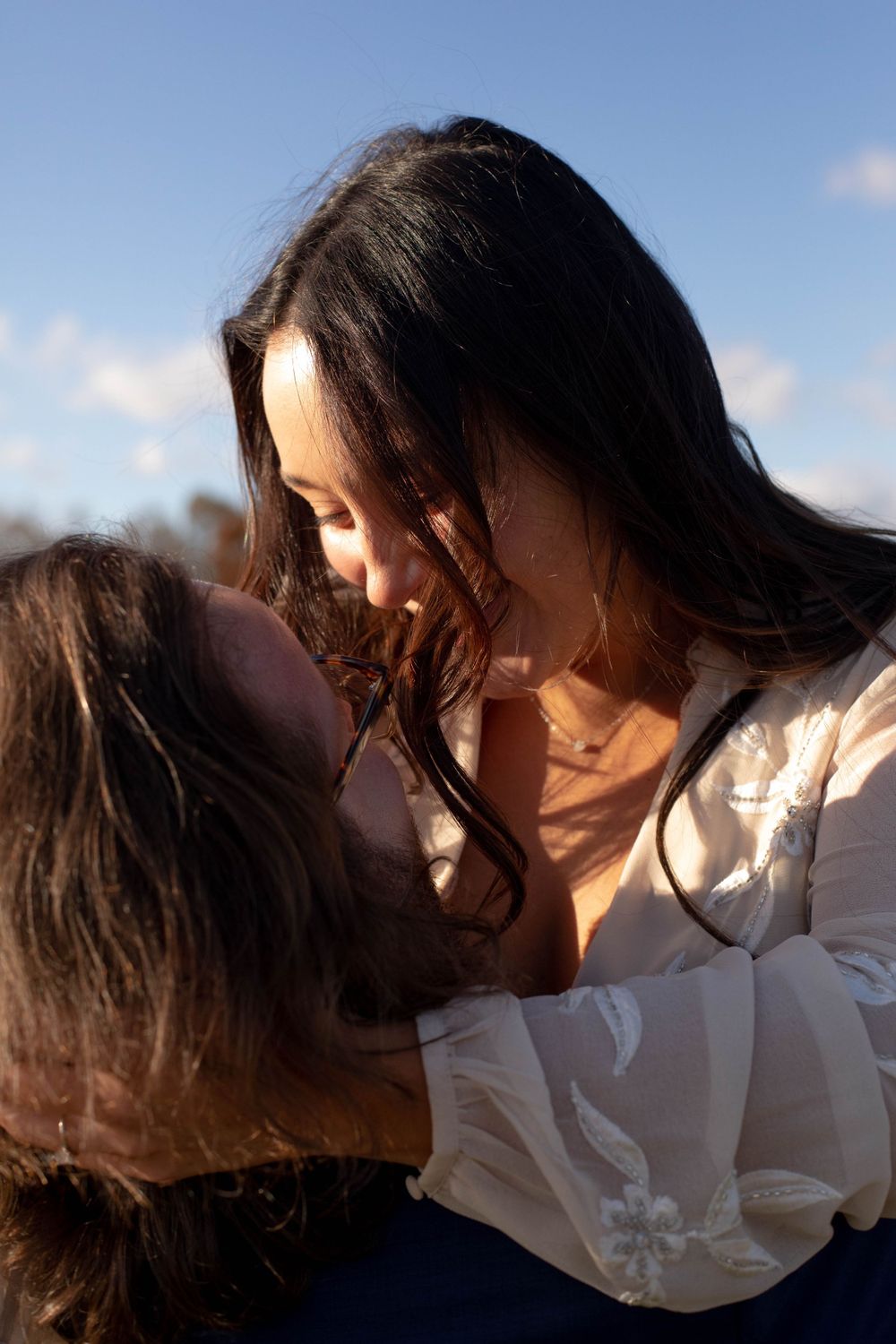 Intimate sunset moment between couple against blue sky.