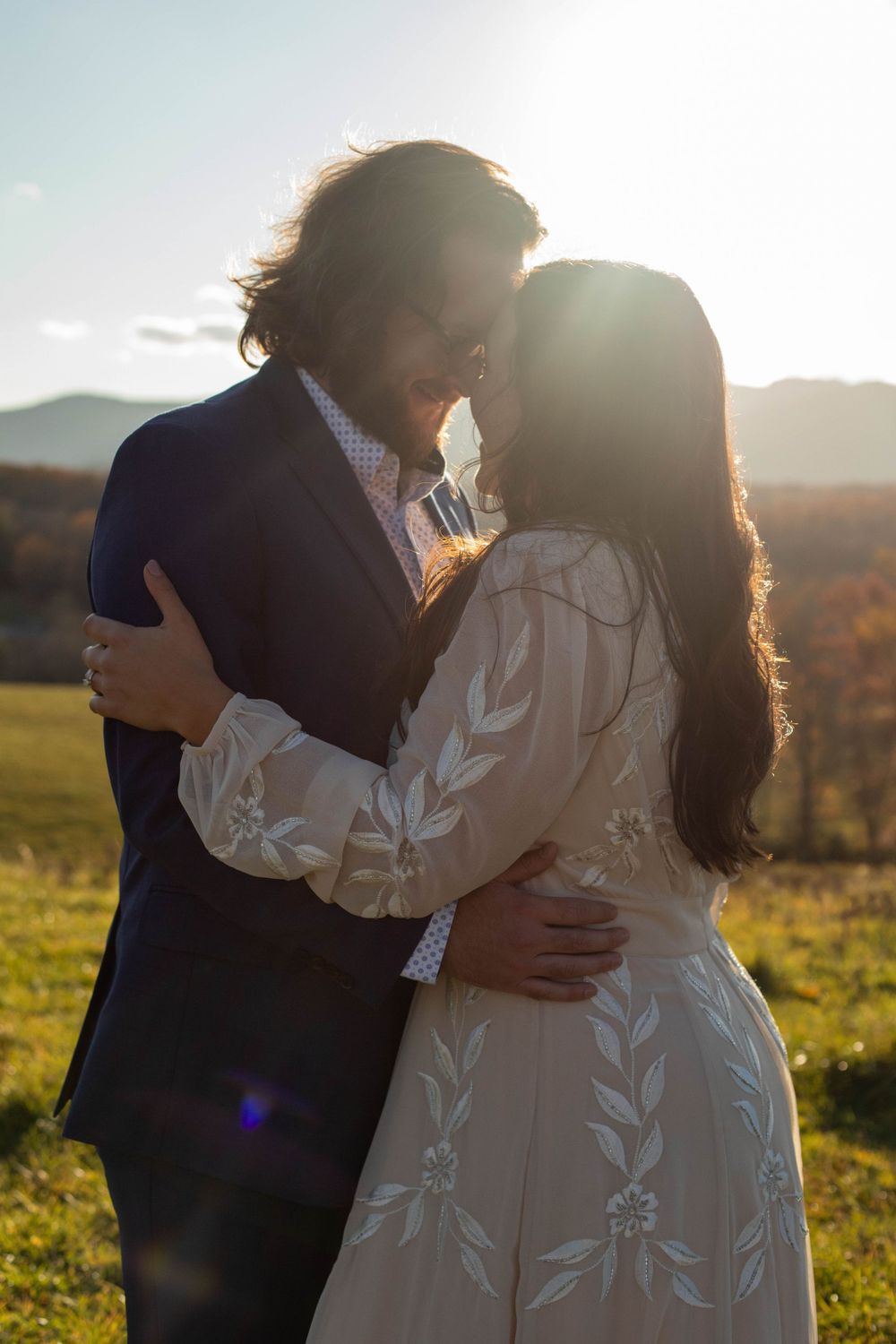 A couple embraces in a sunlit field during golden hour.