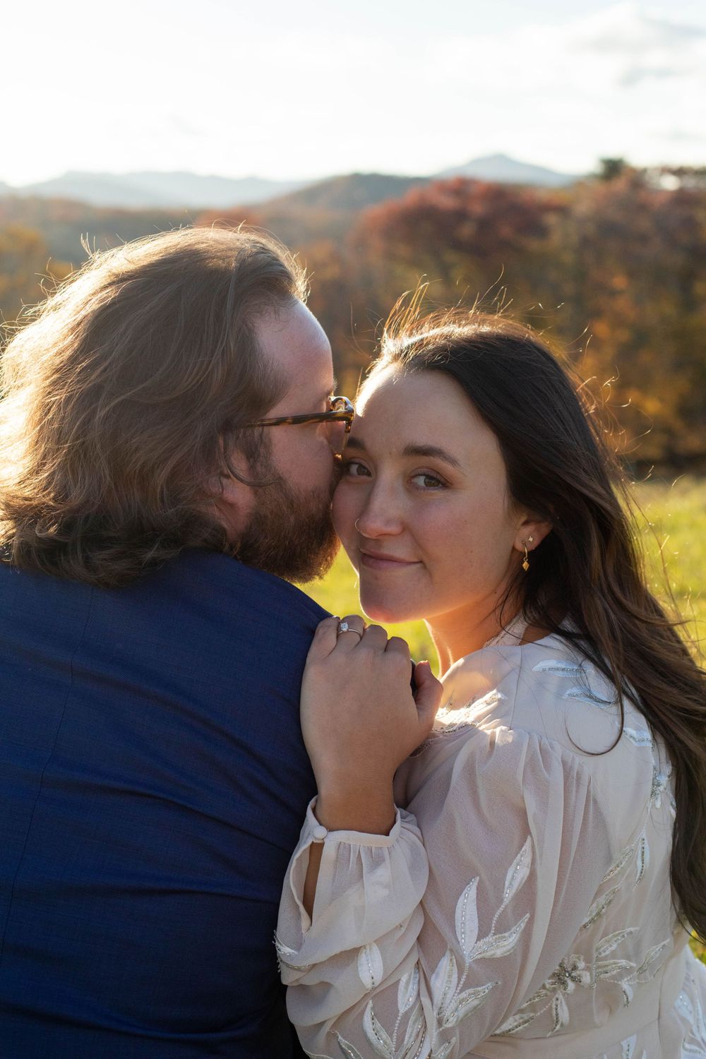 A couple shares an intimate moment in a field during sunset.