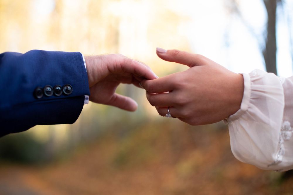 Close-up of hands exchanging rings in natural outdoor lighting.