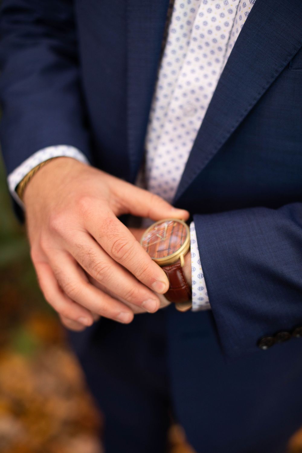 Close-up of hands exchanging rings during an autumn wedding ceremony.