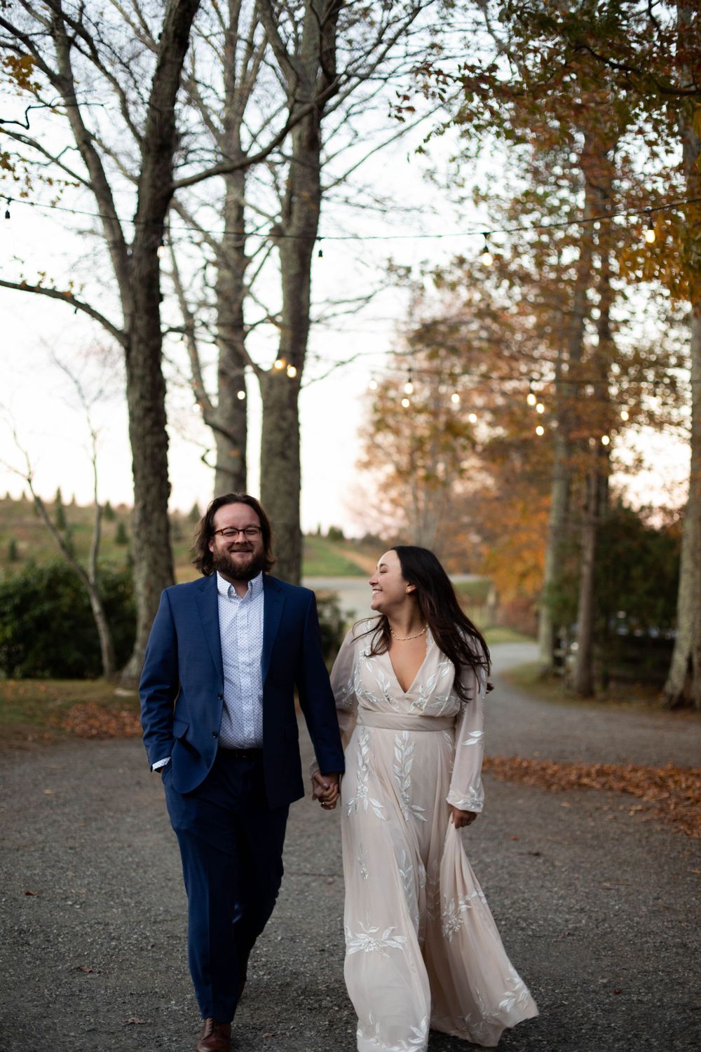 Couple walking together on autumn path surrounded by bare trees.
