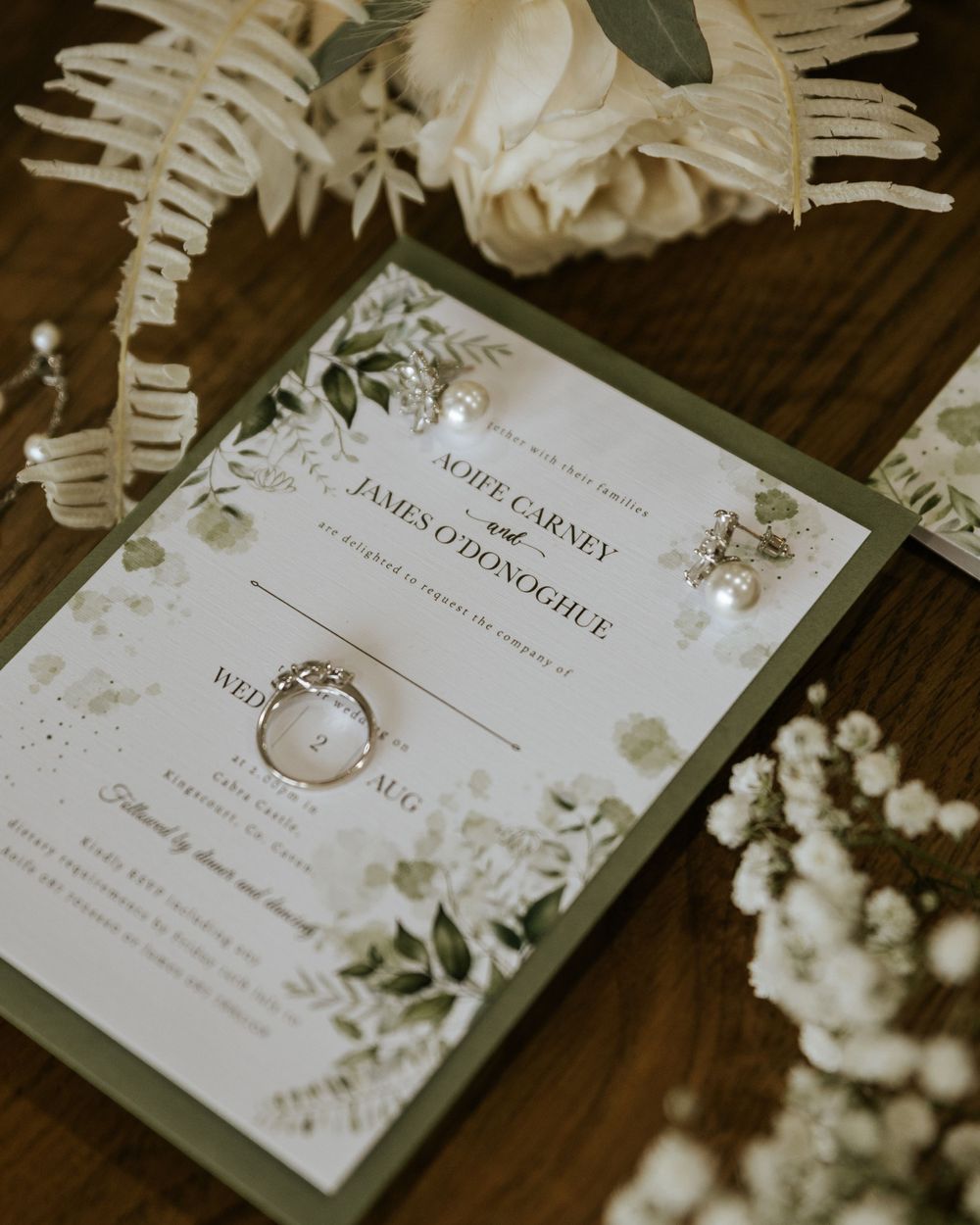 Elegant wedding invitations with floral designs and greenery details.