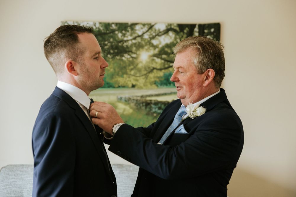 Men in formal suits share drinks and laughter during pre-wedding celebrations.