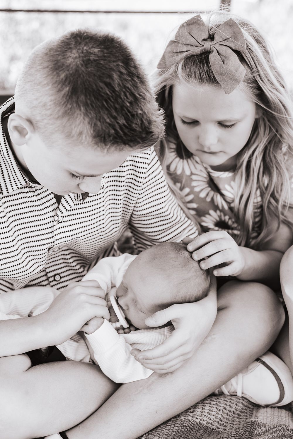 Black and white image of children looking down at something together in a candid moment.