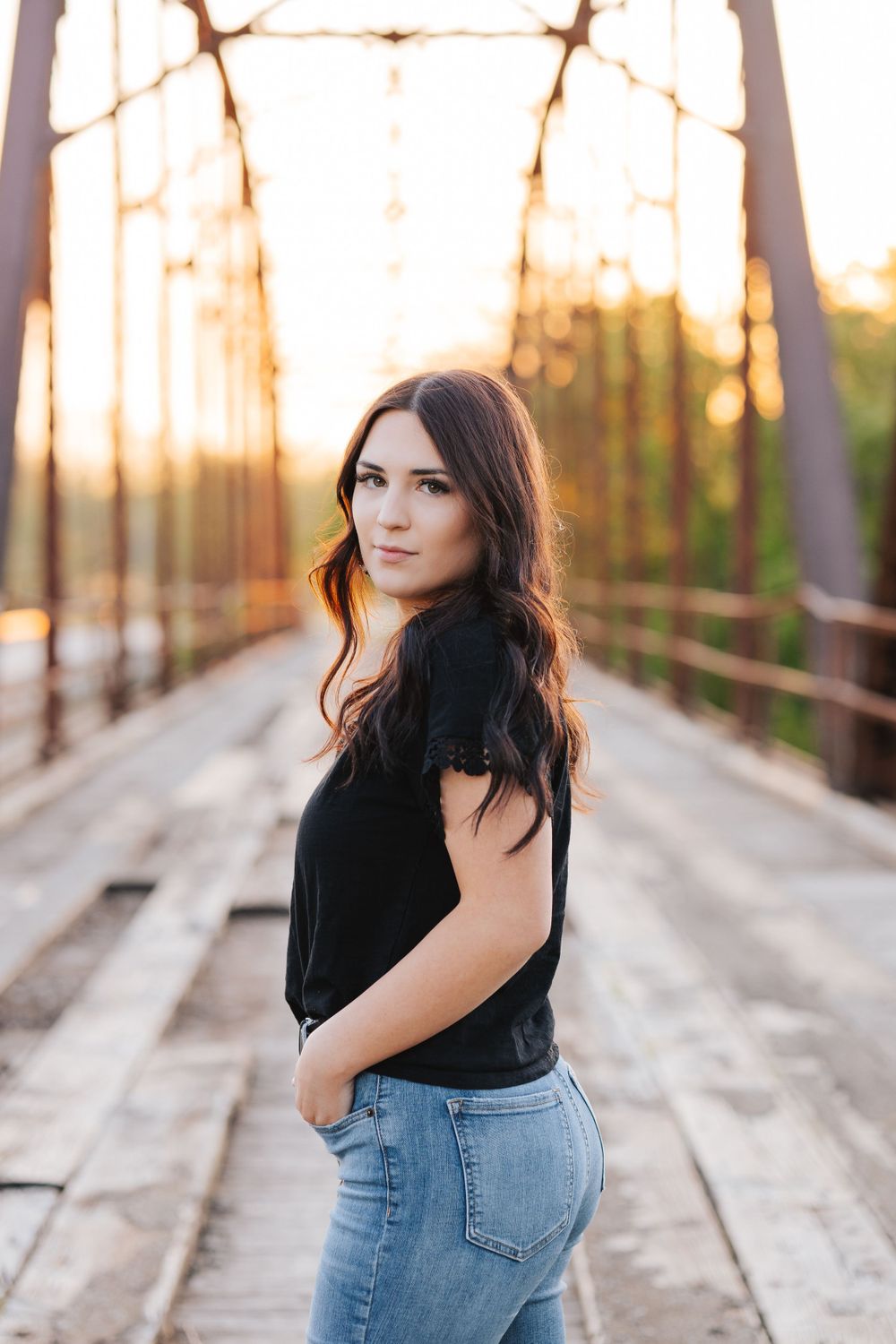 Artistic portrait series on wooden bridge during golden hour showing casual denim style.