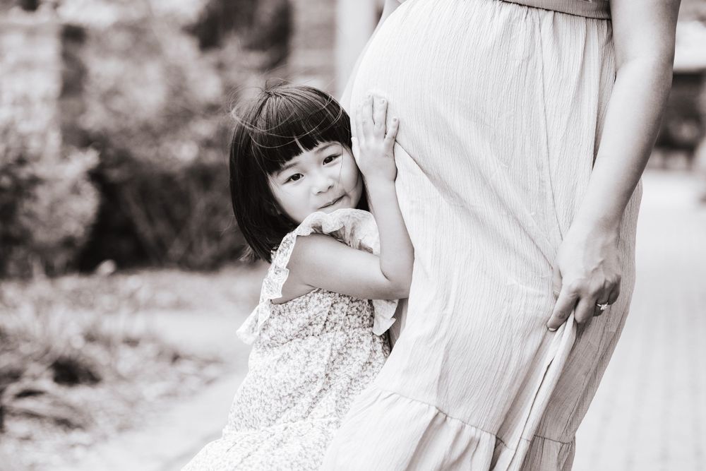 A series of delicate maternity photos showing a pregnant belly in a garden setting.