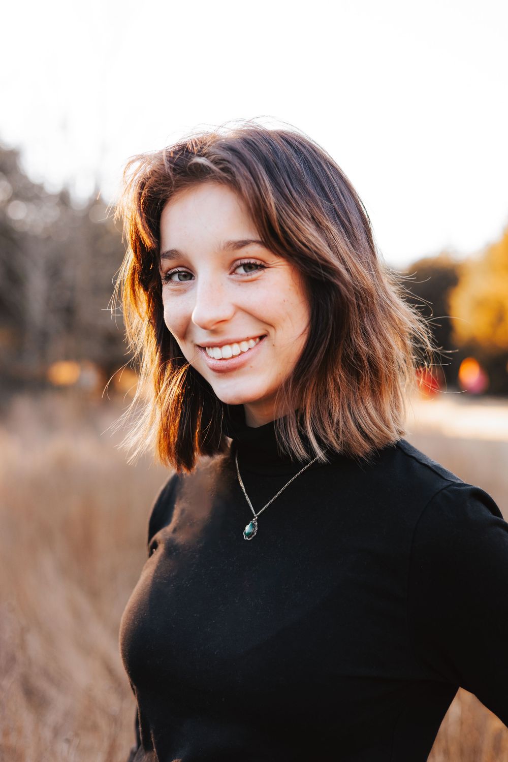 Portrait series in autumn field showing natural expressions and black turtleneck sweater.